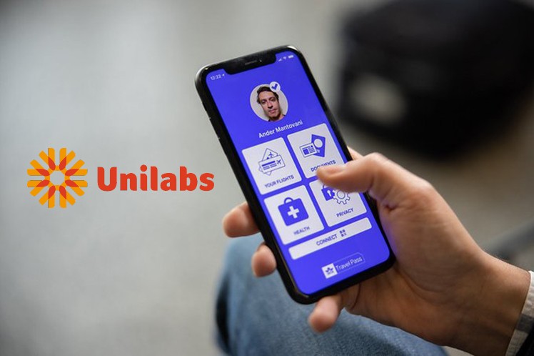 pase de IATA en un smartphone, sostenido por una mano y el logo de Unilabs