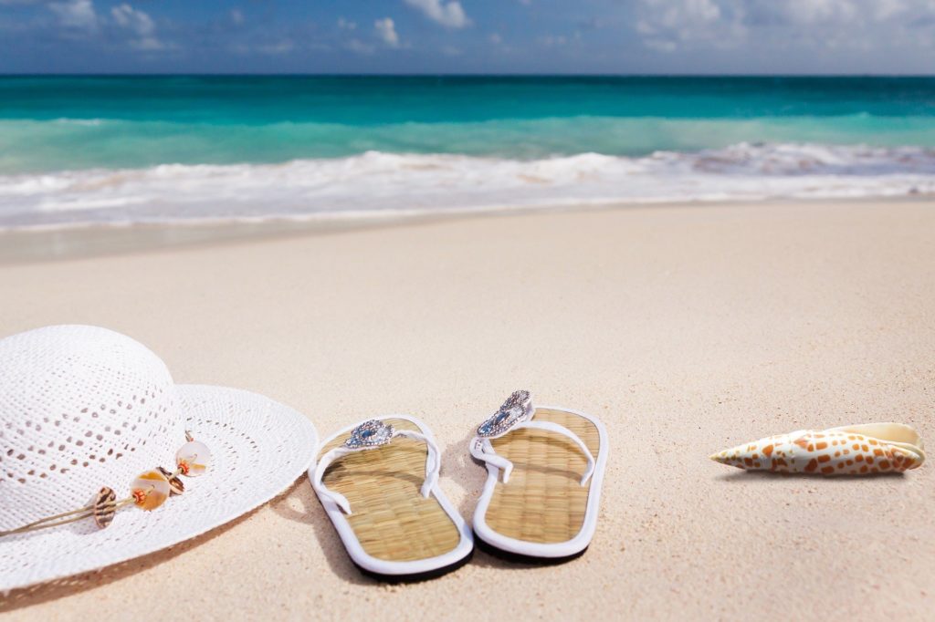 sombrero y sandalias en una playa