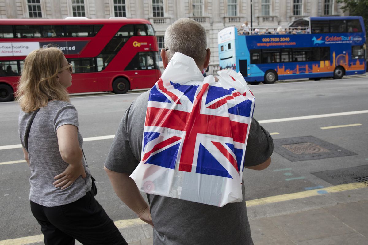 dos turistas británicos de espalda, una bolsa con la bandera británica