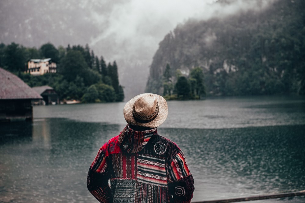 mujer con sombrero de espaldas mirando un lago