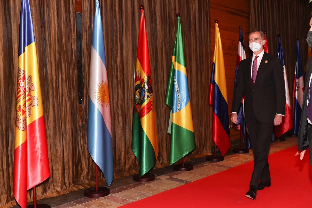 el Rey Felipe VI sobre alfombra roja ante banderas iberoamericanas