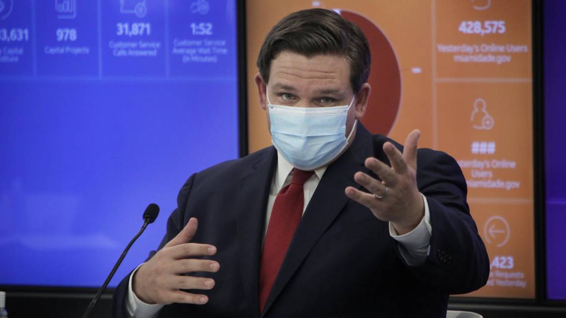 Gov. Ron DeSantis speaking and wearing a face mask