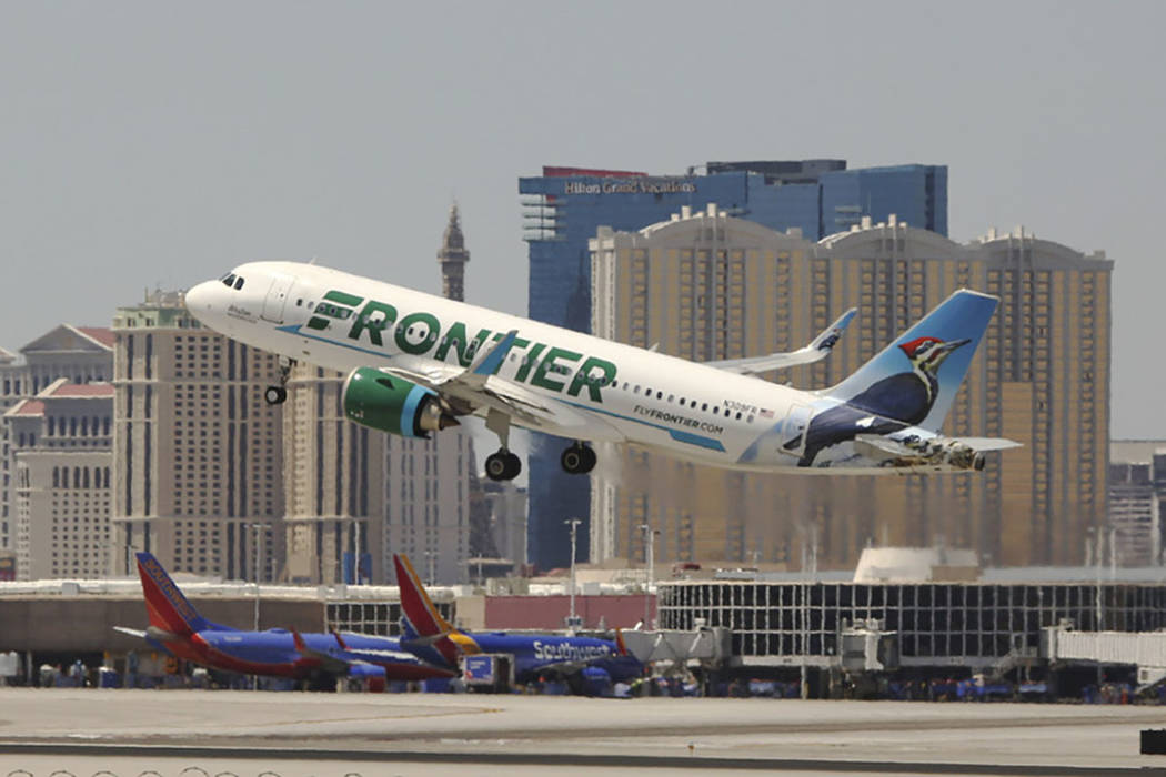 avión de Frontier Airlines despegando, edificios detrás