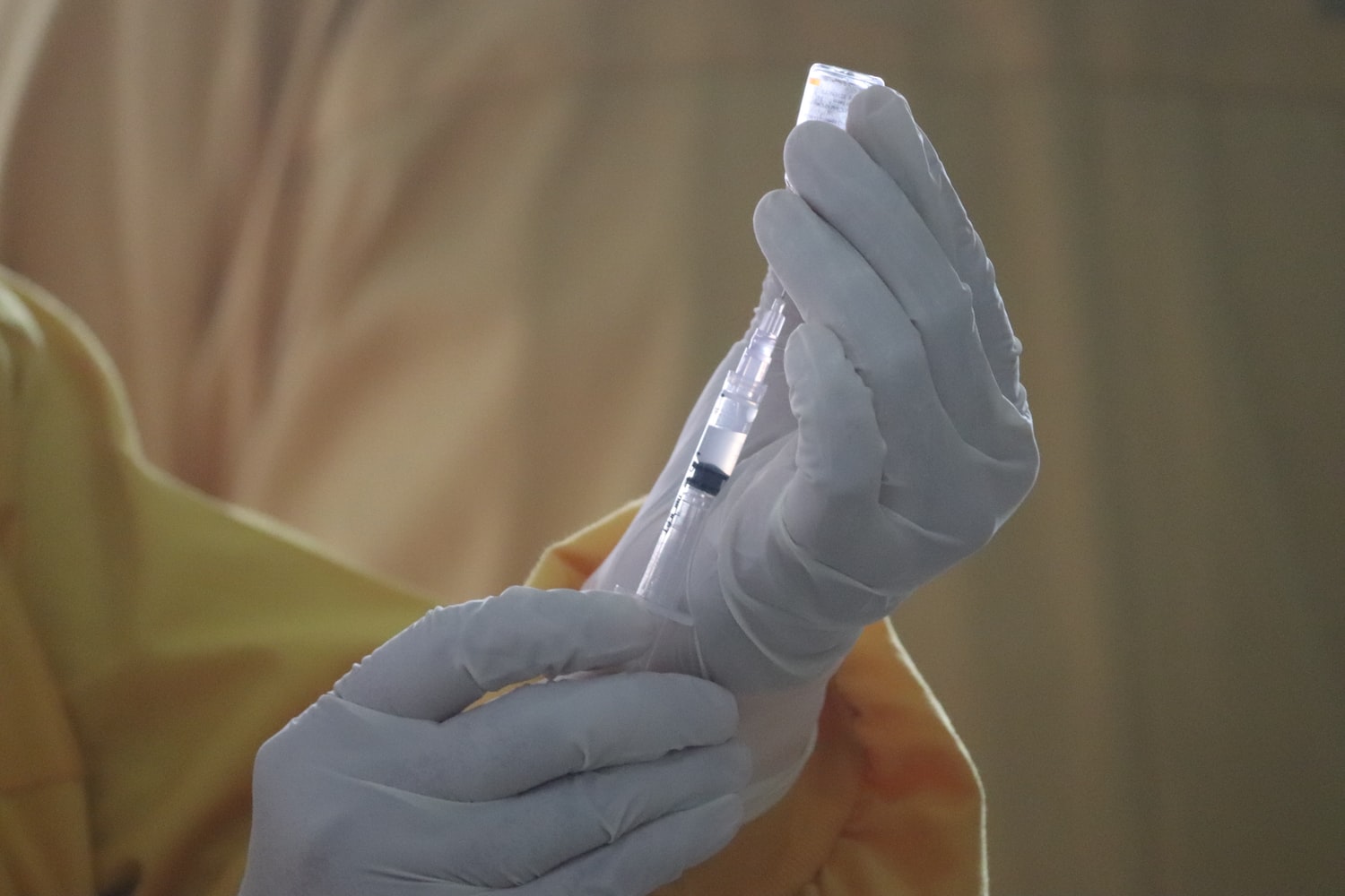 manos enguantadas preparando una dosis de la vacuna contra la Covid 19