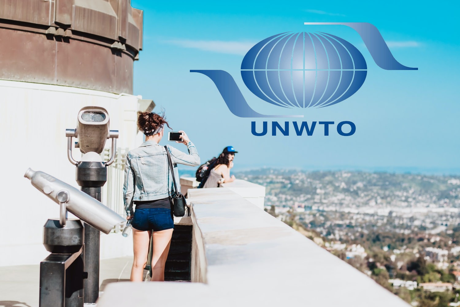dos turistas en una edificio alto y el logo de la OMT