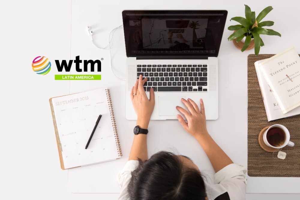 WTM Latin America logo, mujer trabajando en una laptop vista desde arriba