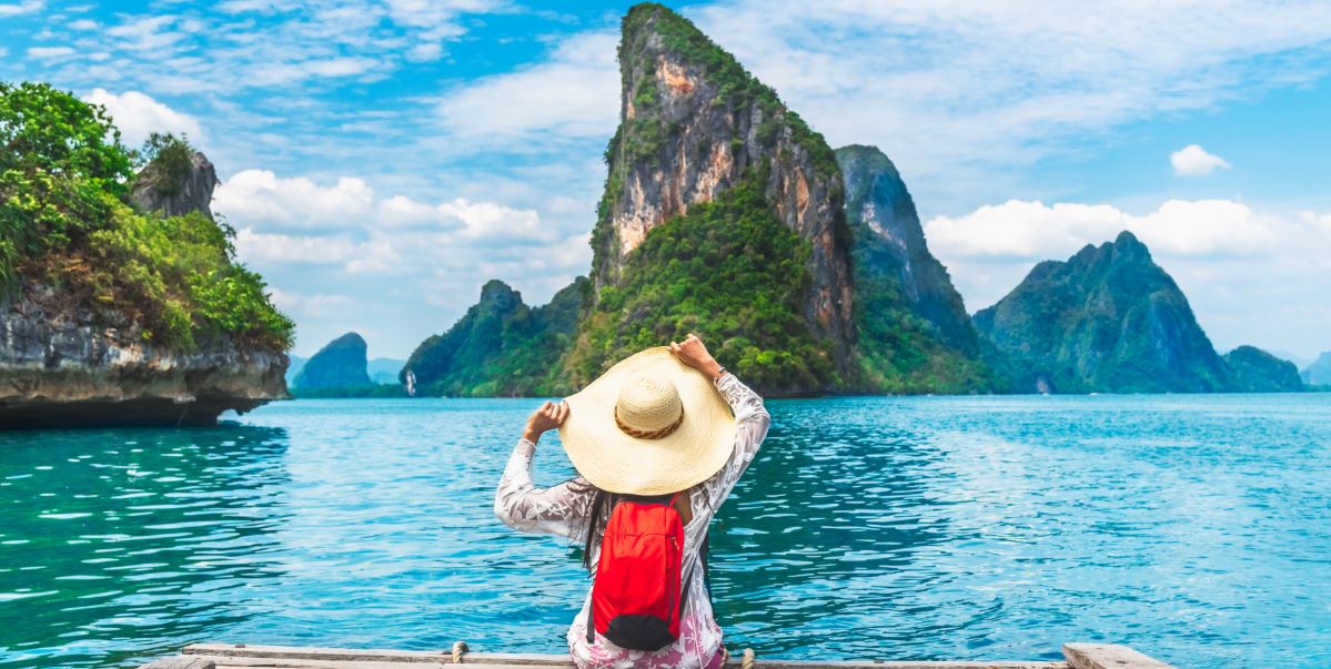 mujer con sombrero contemplando un paisaje de agua y montañas