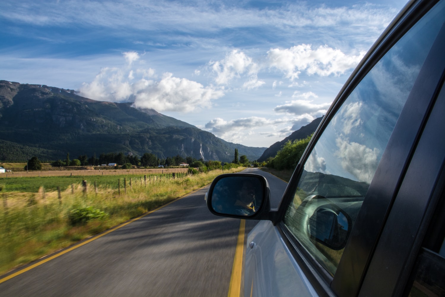 auto por una carretera, espejo retrovisor, montañas a la izquierda